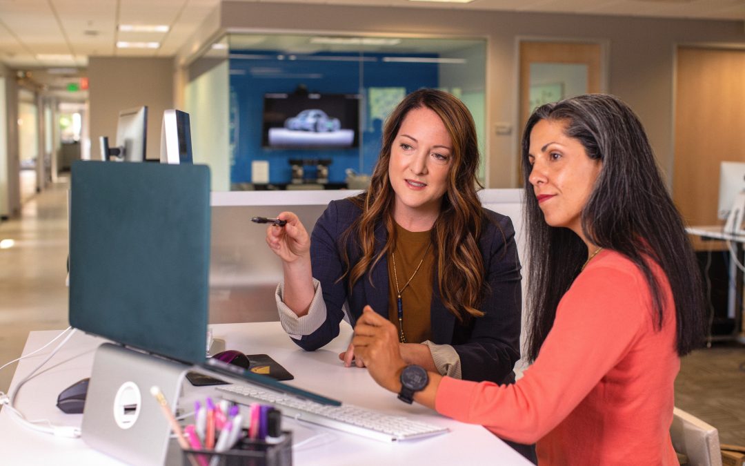 Two women analyzing something on a computer.